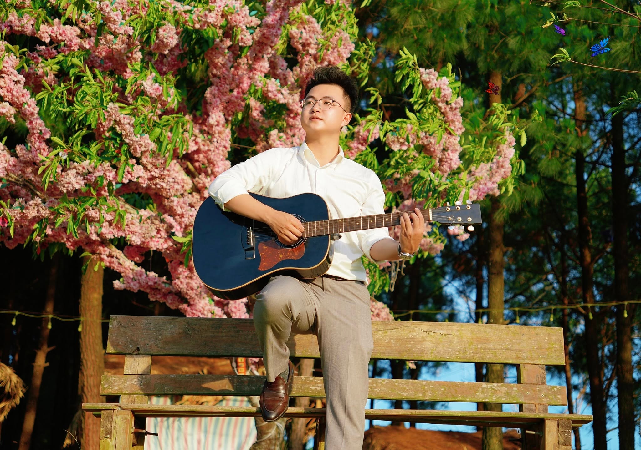 Thầy Trung ôm đàn guitar dưới tán hoa